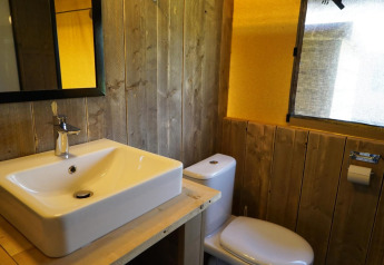 Baño con paredes de madera, lavabo moderno, espejo y WC en una tienda safari en Molengroet, Países Bajos.