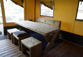 Zona de comedor con mesa y bancos de madera rústica en una tienda safari de Molengroet, Países Bajos.
