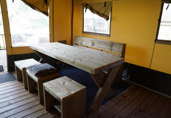 Essbereich mit rustikalem Holztisch und Bänken in einem Safarizelt der Molengroet Lodge in den Niederlanden.