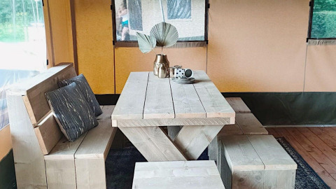 Træmøbleret spisebord med bænk og puder i en safariteltslodge ved Molengroet i Nederlandene.
