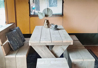 Træmøbleret spisebord med bænk og puder i en safariteltslodge ved Molengroet i Nederlandene.