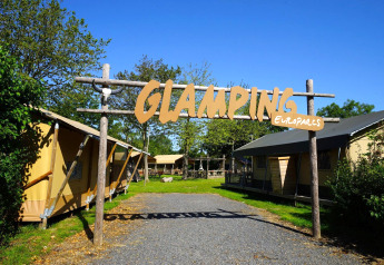 Indgang til glampingområde med safaritelte og skilt ved Molengroet i Holland, omgivet af grøn natur.