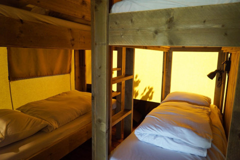 Indre af en safariteltlodge på Molengroet i Holland, der viser køjesenge med blødt sengetøj.