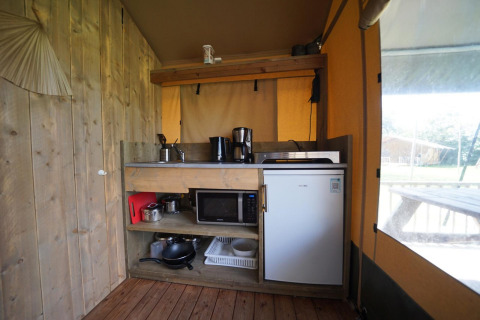 Küchenbereich eines Safari-Zeltes im Molengroet, Niederlande, mit Kühlschrank, Mikrowelle und Geräten.