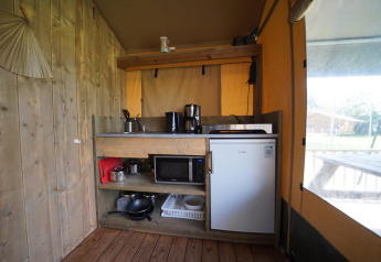 Coin cuisine d'une tente Safari à Molengroet, Pays-Bas, avec frigo, micro-ondes et ustensiles.