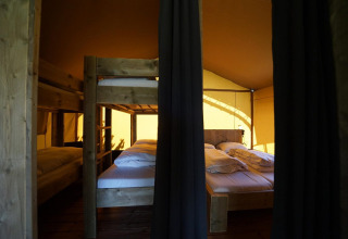 Indvendig udsigt af Safari telt på Molengroet, Nederlandene, med køjesenge og dobbeltseng.