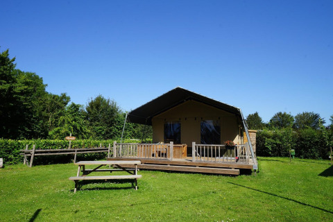 Safarizelt in Molengroet, Niederlande, mit hölzerner Terrasse und Sitzbank auf grüner Wiese.