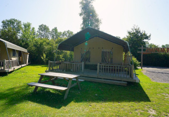 Safari tent at Molengroet in the Netherlands with wooden deck, picnic table, and grassy outdoor area.