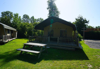 Safari-Zelt bei Molengroet in den Niederlanden mit Holzterrasse, Picknicktisch und grüner Rasenfläche.