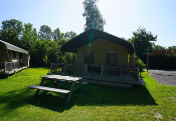 Safari-Zelt bei Molengroet in den Niederlanden mit Holzterrasse, Picknicktisch und grüner Rasenfläche.