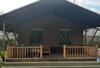 Tienda de glamping Country en Molengroet, Países Bajos, con porche de madera y zona verde abierta.