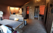 Interior de tienda glamping en Molengroet, Países Bajos, con muebles de madera, comedor y cocina equipada.