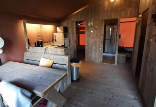 Interior de tienda glamping en Molengroet, Países Bajos, con muebles de madera, comedor y cocina equipada.