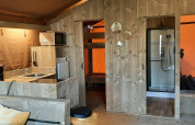 Indvendig udsigt over Glampingtent Country ved Molengroet, Holland, med køkken, køjeseng og bruser.