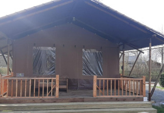 Glampingtent Country en Molengroet, Países Bajos, con porche cubierto y barandillas de madera en la entrada.