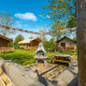 Vista exterior de una cabaña tipo lodge con tiendas, bancos de madera, césped y zona de estar al aire libre.