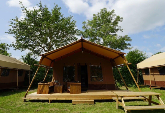Foto exterior de la Glampingtent Desert con terraza de madera, zona de asientos y rodeada de vegetación.