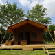 Udendørsbillede af Glampingtent Desert-lodgen med træterrasse og bordbænkesæt, omgivet af træer.