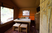 Vista interior de Glampingtent Desert en Molengroet, Países Bajos, con muebles de madera y atrapasueños.
