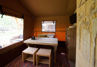 Vista interior de Glampingtent Desert en Molengroet, Países Bajos, con muebles de madera y atrapasueños.