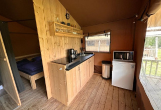 Binnenzicht van Glampingtent Desert in Molengroet, Nederland, met keukenhoek en slaapkamer zichtbaar.