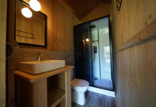 Baño moderno con paredes de madera, lavabo, inodoro y ducha en Glampingtent Desert, Molengroet, Países Bajos.
