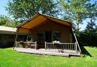 Vista exterior de la Glampingtent Desert en Molengroet, Países Bajos, con terraza de madera y césped verde.