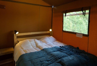 Dormitorio acogedor con cama doble y lámparas de lectura en Glampingtent Desert, Molengroet, Países Bajos.