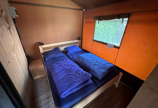 Área de dormir acogedora con dos camas individuales y ropa de cama azul en Glampingtent Desert, Molengroet, Países Bajos.