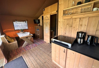 Vista interior de Glampingtent Desert en Molengroet, Países Bajos, con muebles de madera y cocina pequeña.