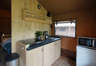Cocina interior de Glampingtent Desert en Molengroet, Países Bajos, con estufa, fregadero y refrigerador.