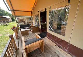 Terrazza esterna della Glampingtent Desert a Molengroet, Paesi Bassi, con arredi in legno e tettoia.