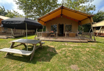 Glampingtelt Desert ved Molengroet i Holland med terrasse, borde og parasol under grønne træer.