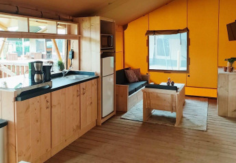 Interno della Glampingtent Dreamer presso Molengroet nei Paesi Bassi, con soggiorno accogliente e angolo cottura.