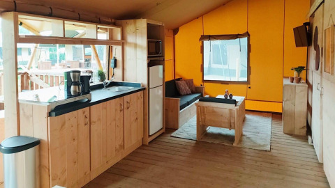 Intérieur de Glampingtent Dreamer à Molengroet aux Pays-Bas, avec salon convivial et coin cuisine en bois.