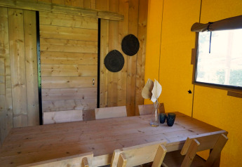 Tavolo in legno con sedie e decorazioni nella Glampingtent Dreamer al Molengroet, Paesi Bassi