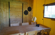 Holztisch mit Stühlen und Dekorationen in der Glampingtent Dreamer Lodge bei Molengroet, Niederlande