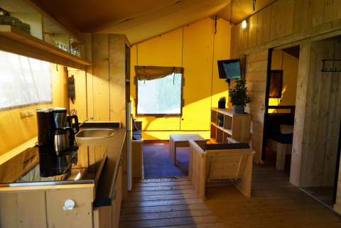 Binnenkant van Glampingtent Dreamer lodge op Molengroet in Nederland met houten meubels en keuken.