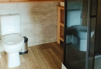 Modernes Badezimmer mit Toilette, Dusche und Mülleimer im Glampingtent Dreamer, Molengroet, Niederlande.