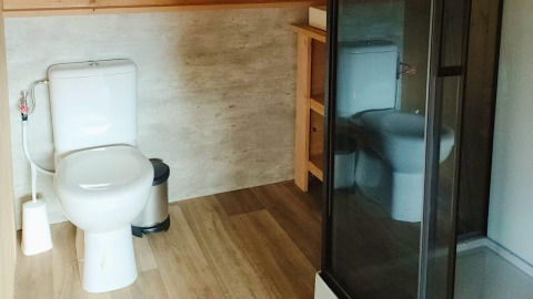 Moderne badkamer met toilet, prullenbak en douche in Glampingtent Dreamer, Molengroet, Nederland.