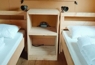 Twee eenpersoonsbedden met wit beddengoed, gescheiden door een houten kast bij Glampingtent Dreamer, Molengroet.