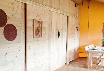 Interno del Glampingtent Dreamer al Molengroet nei Paesi Bassi con pareti in legno e zona pranzo.