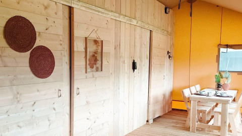 Interno del Glampingtent Dreamer al Molengroet nei Paesi Bassi con pareti in legno e zona pranzo.
