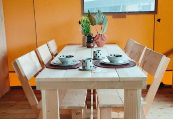 Mesa de comedor de madera para cuatro con vajilla y plantas en Glampingtent Dreamer, Molengroet, Países Bajos.