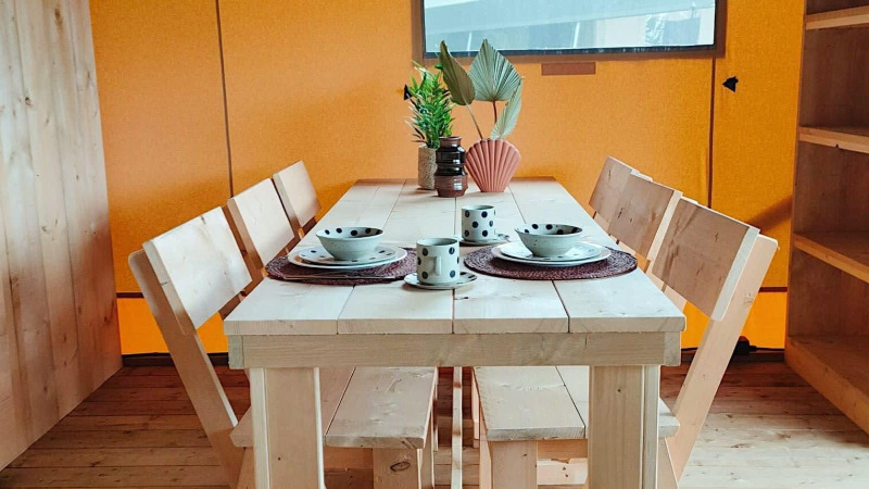 Mesa de comedor de madera para cuatro con vajilla y plantas en Glampingtent Dreamer, Molengroet, Países Bajos.