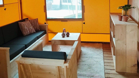 Interior del Glampingtent Dreamer en Molengroet, Países Bajos, con muebles de madera y paredes amarillas.