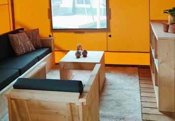 Interieur van Glampingtent Dreamer bij Molengroet, Nederland met houten meubels en gele wanden.
