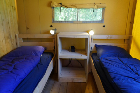 Zwei Einzelbetten mit blauer Bettwäsche und Nachttisch in Glampingtent Dreamer, Molengroet, Niederlande.