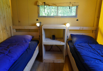 Zwei Einzelbetten mit blauer Bettwäsche und Nachttisch in Glampingtent Dreamer, Molengroet, Niederlande.
