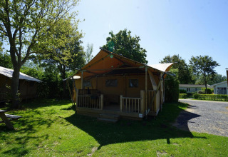 Udendørs scene med Glampingtent Dreamer på Molengroet i Holland, omgivet af træer og grønt græs.